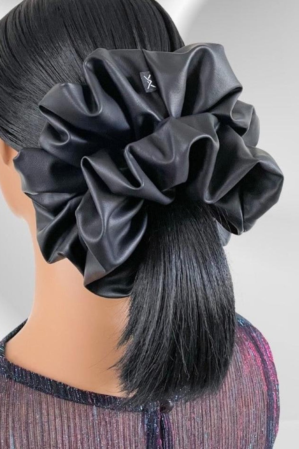 Big black leather scrunchie worn on a low ponytail