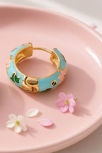 Lotus Lagoon Huggie Earrings – turquoise enamel lotus huggies on a pink dish