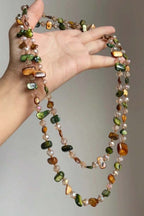 Mermaid Wrap Necklace held in hand – green and amber shell chips with crystal beads