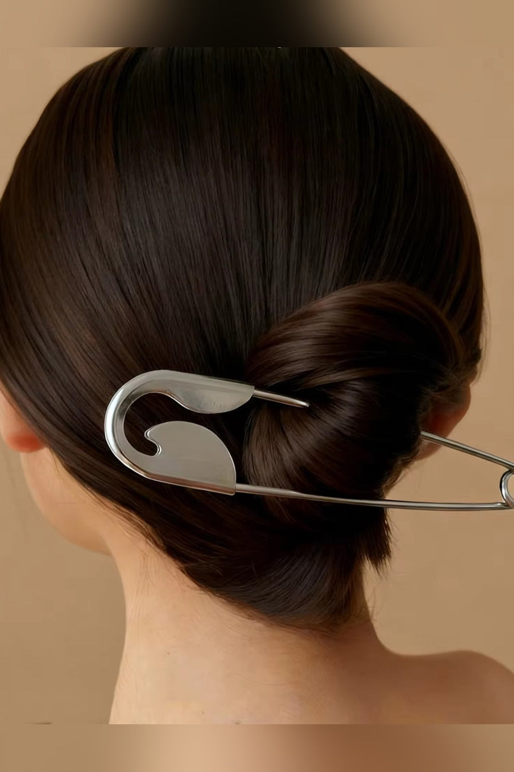 Oversized silver safety pin hair pin worn in a low bun