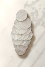 White Shell Cascade Earrings – white capiz shell disc drop earring on white marble in warm golden-hour sunlight