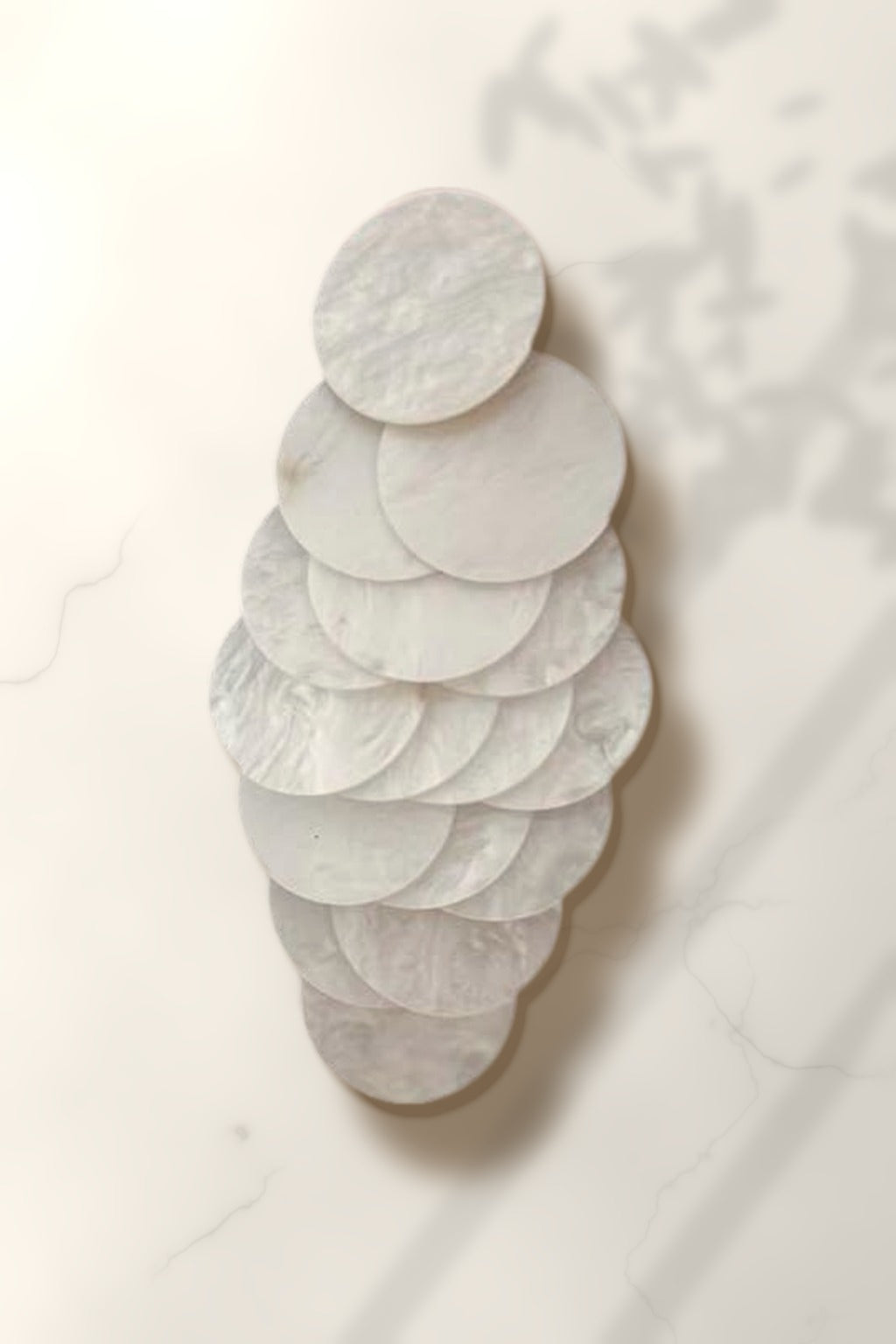White Shell Cascade Earrings – white capiz shell disc drop earring on white marble in warm golden-hour sunlight