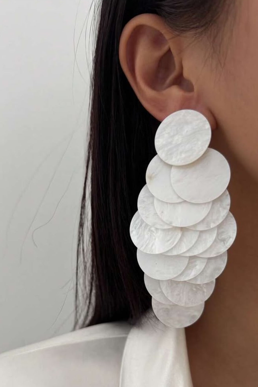 White Shell Cascade Earrings worn on the ear – white shell disc cascade drop